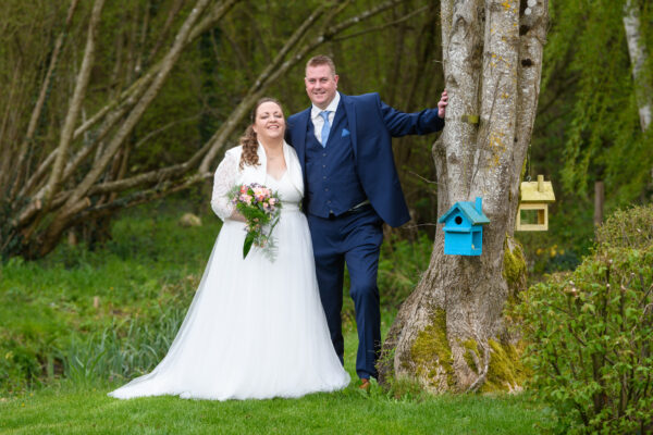 portrait couple de mariés avec un arbre et des cabanes à oiseaux de couleur