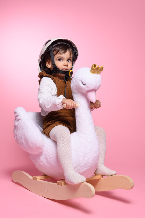 portrait enfant amusant petite fille portant un casque sur un cygne a bascule