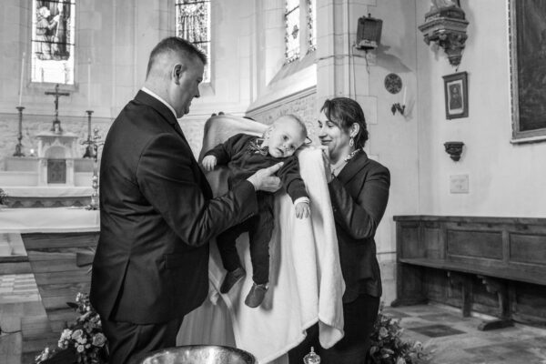 baptême enfant le père mets l’enfant dans une couverture