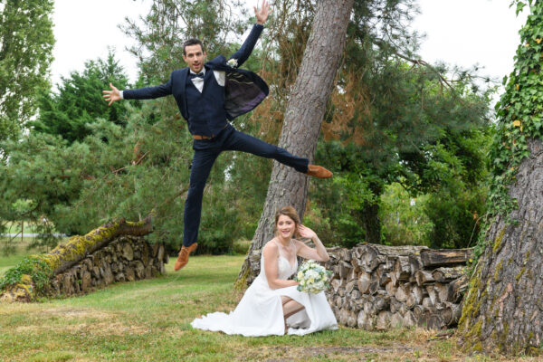 marié sautant dans la nature au dessus de la mariée
