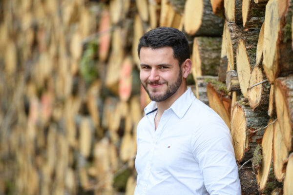 portrait homme avec en arrière plan du bois coupé