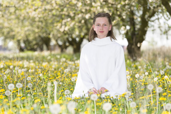 portrait communiante au milieu de fleurs de pissenlit et des fruitiers en fleur
