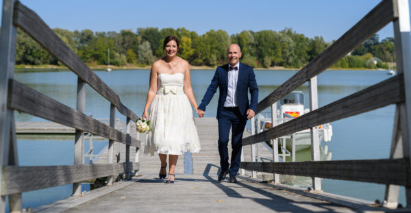 mariés marchant sur un pont devant un lac