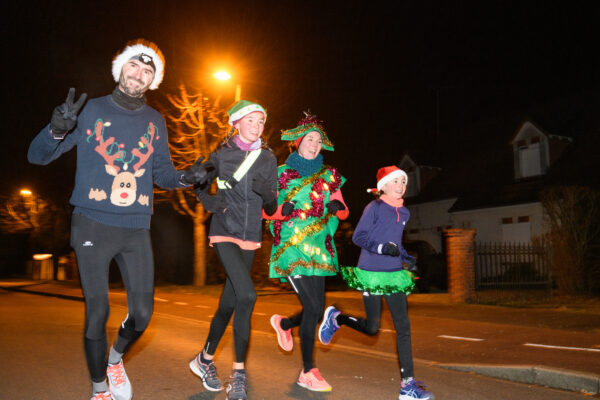 course de noël à Olivet deux adultes et deux enfants courant avec des bonnets de noël