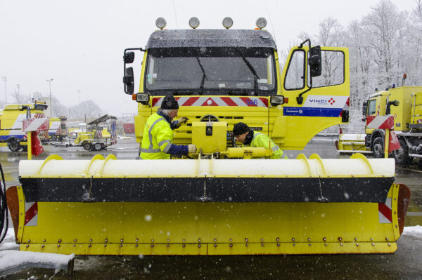 Vinci Cofiroute deux personnes entretiennent une déneigeuse sous la neige