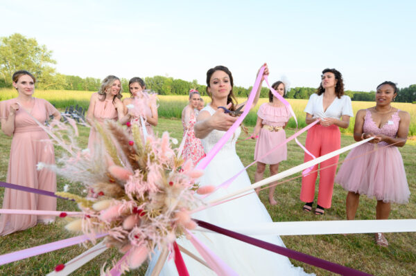 mariée coupant le ruban dans la ronde du ruban entourée de jeunes femmes