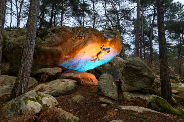 killian chabrier grimpeur sur un rocher dans la forêt de fontainebleau avec lumière colorée