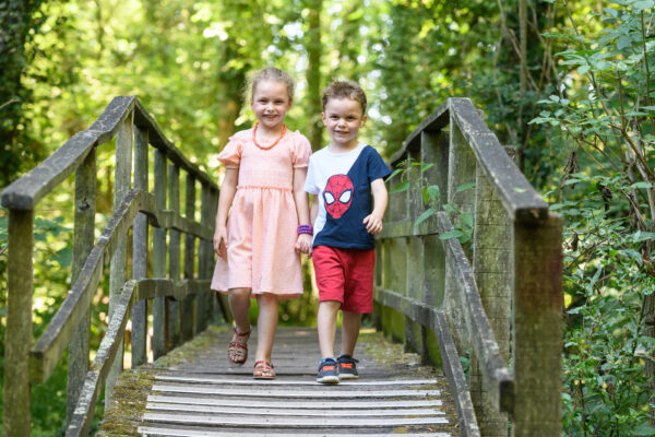 portrait de deux enfants marchant sur un pont en bois dans la nature