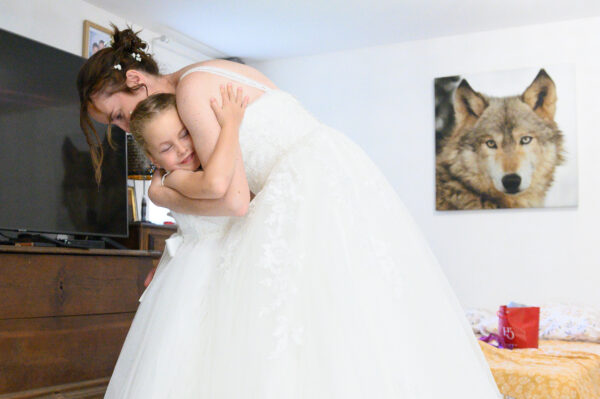 mariée faisant un câlin à sa fille devant une photo de visage de loup les regardant