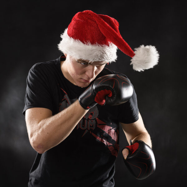 portrait amusant d'un jeune boxant le pompon de son bonnet de noël