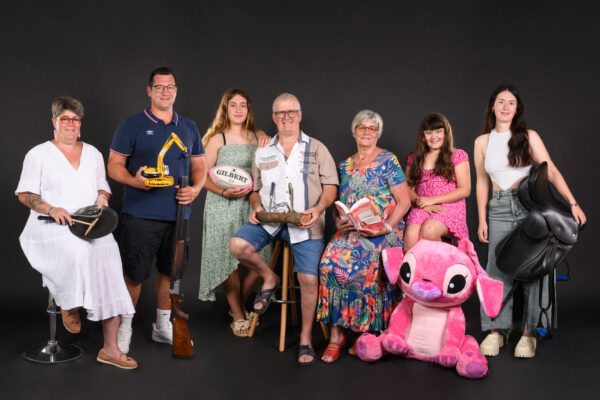 portrait d'une grande famille en studio chacun ayant dans ses mains un objet qui représente sa passion