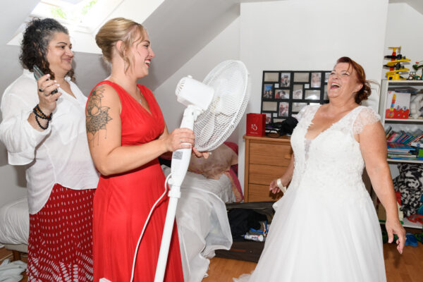 mariée riant en se rafraichissant avec un ventilateur