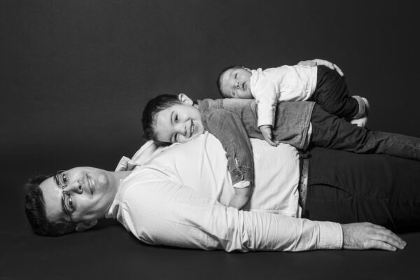 portrait papa avec ses deux fils posés sur son ventre noir et blanc