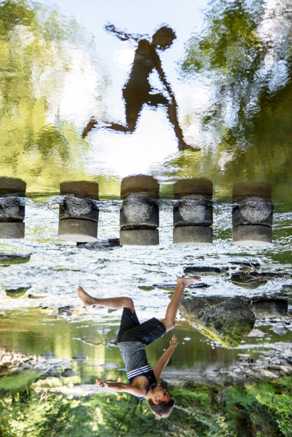 reflet d'au l'eau d'un jeune garçon sautant au dessus de l'eau