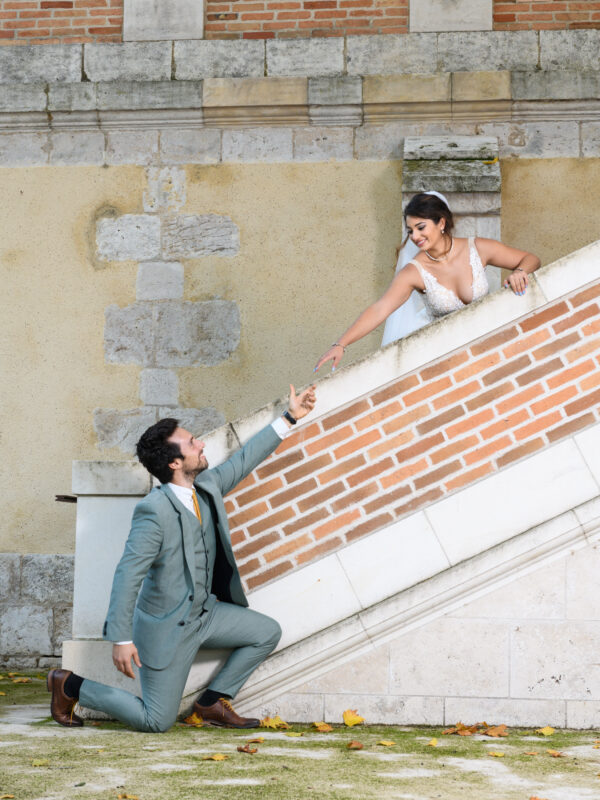 portrait couple de mariés séparés sur un escalier cherchant à se donner la main