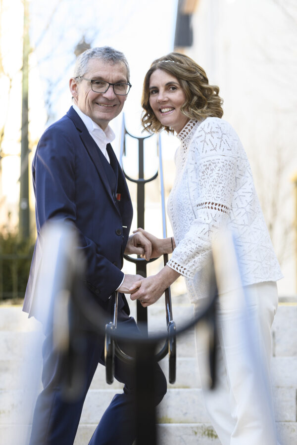 portrait de couple de mariés derrière une rambarde d'escalier