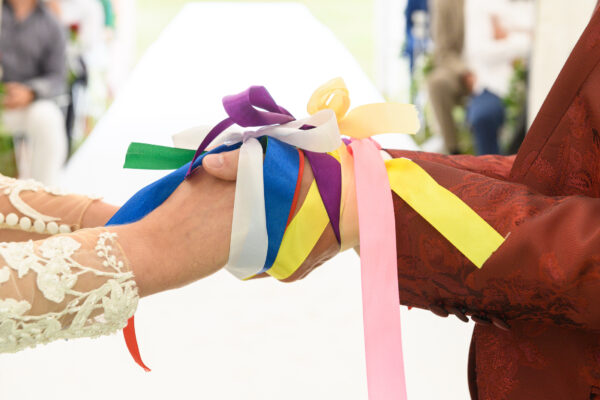 mariage laïque mains des mariés attachés par des rubans
