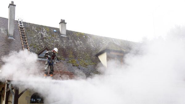 traitement de toiture par UAB homme nettoyant une toiture avec de l'eau chaude