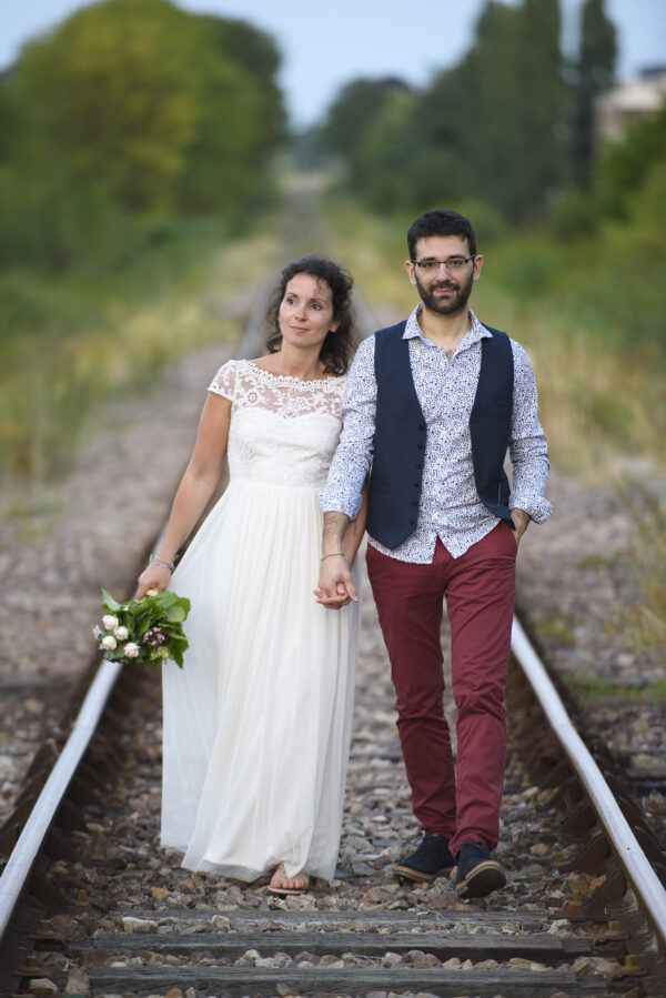 couple de marié marchant au milieu de rails de chemin de fer