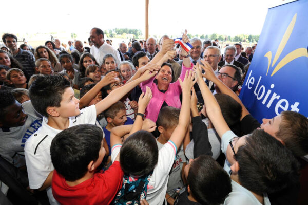 Pauline martin distribuant des morceaux de rubans tricolore à des enfants lors d'une inauguration