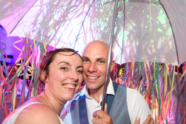 mariés sous un parapluie entourés de serpentins