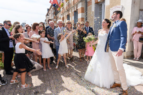 mariés à la sortie de la mairie des gens jettent des confettis