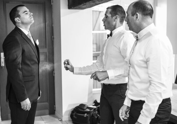 habillage du marié avec ses témoins lui mettant du parfum