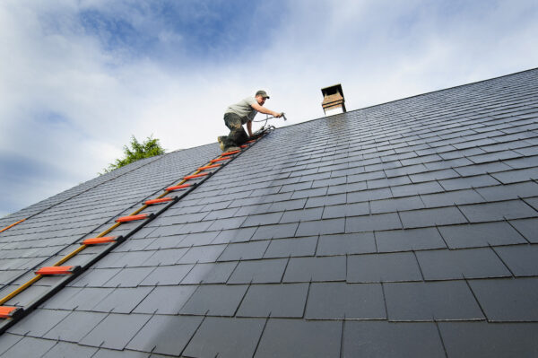 traitement de toiture par UAB homme peignant une toiture au pistolet