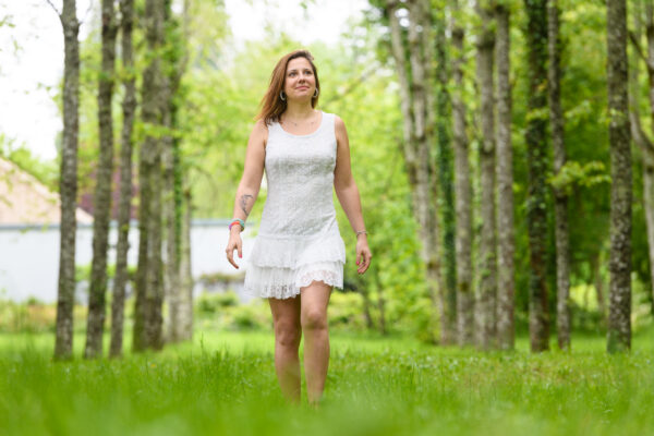 portrait d'une femme marchant au milieu d'une rangée d'arbres