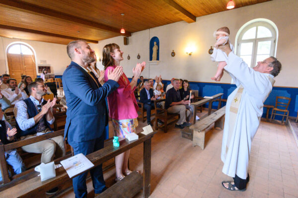 baptême dans une église le prêtre brandit l'enfant façon le roi lion