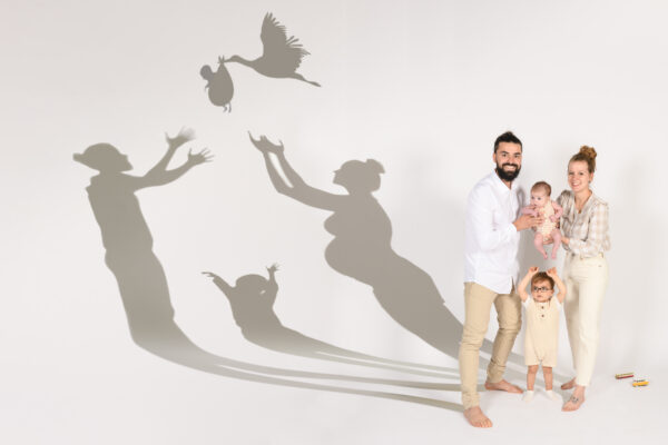 portrait famille femme enceinte original avec ombres et arrivée du bébé avec cigogne