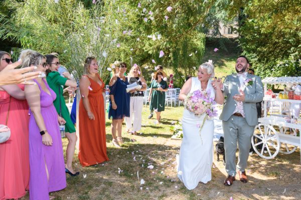mariés sortant de la cérémonie les invités lançant des pétales de rose