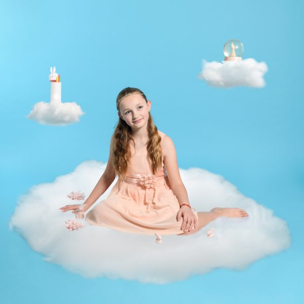 Portrait onirique d'une petite fille dans les nuages avec ses objets favoris